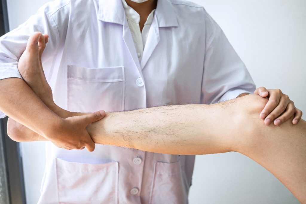 Doctor Or Physiotherapist Working Examining Treating Injured Leg