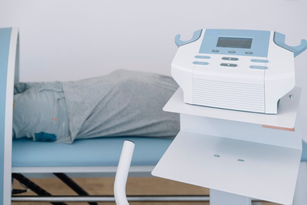 The Physiotherapist Treating A Man Using Equipment For Radio Therapy